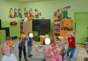 Zdjęcie przedstawia kilkoro dzieci z grupy I i II biorących udział w zabawie ruchowej połączonej z ćwiczeniami oddechowymi.