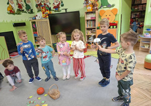 Zdjęcie przedstawia kilkoro dzieci tworzących scenkę z wykorzystaniem kukiełek zwierząt występujących w bajce.