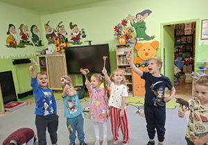 Zdjęcie przedstawia kilkoro dzieci tworzących scenkę z wykorzystaniem kukiełek zwierząt występujących w bajce.